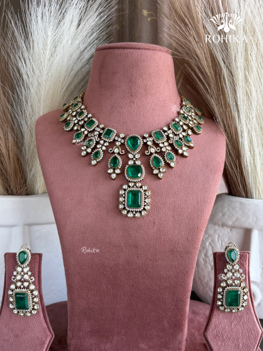 Jewelry set with emerald green stones on a mannequin bust, brand 'Rohika' visible.