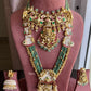Gold and green jewelry set on a pink mannequin with 'Rohika' branding.